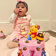 Maria joined the competition — help win amazing prizes! baby, child, cake, pink_cake, frosting, winnie_the_pooh, tigger, eeyore, honey_pot, bees, toy, bow, overalls, sitting, cupcake, carpet, white_wall, smiling, celebration, shoe