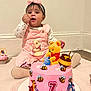baby, child, cake, pink_cake, frosting, winnie_the_pooh, tigger, eeyore, honey_pot, bees, toy, bow, overalls, sitting, cupcake, carpet, white_wall, smiling, celebration, shoe