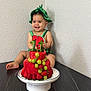 baby, child, fruit_cake, watermelon, grapes, strawberries, smiling, birthday, hat, table, plate, celebration, cute, indoors, person, happy, food, cake, fruit, wall