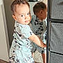 toddler, child, mirror, reflection, carpet, pajamas, mickey_mouse, indoor, curly_hair, foot, standing, clothing, face, expression, furniture, storage_unit, wall, light, person, room