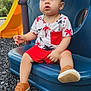 toddler, child, playground, slide, sunglasses, blue_seat, outdoor, shorts, shirt, shoes, gold_chain, red_pocket, plastic_playground_equipment, sunny, grass, trees, black_rubber_ground, casual_clothing, cute, young_child