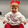 toddler, child, baby, red_bows, sweater, white_sweater, red_leggings, patterned_leggings, smiling, happy, sitting, indoor, cute, portrait, face, hands, hair, clothing, young_child, adorable