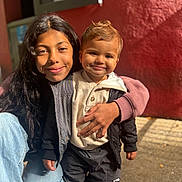 Aaron participe au concours pour gagner de l'argent avec cette photo : child, toddler, smiling, portrait, outdoor, sunlight, jacket, hoodie, jeans, sneakers, siblings, happy, cute, warm_clothing, person, standing, red_wall, candid, casual, daylight