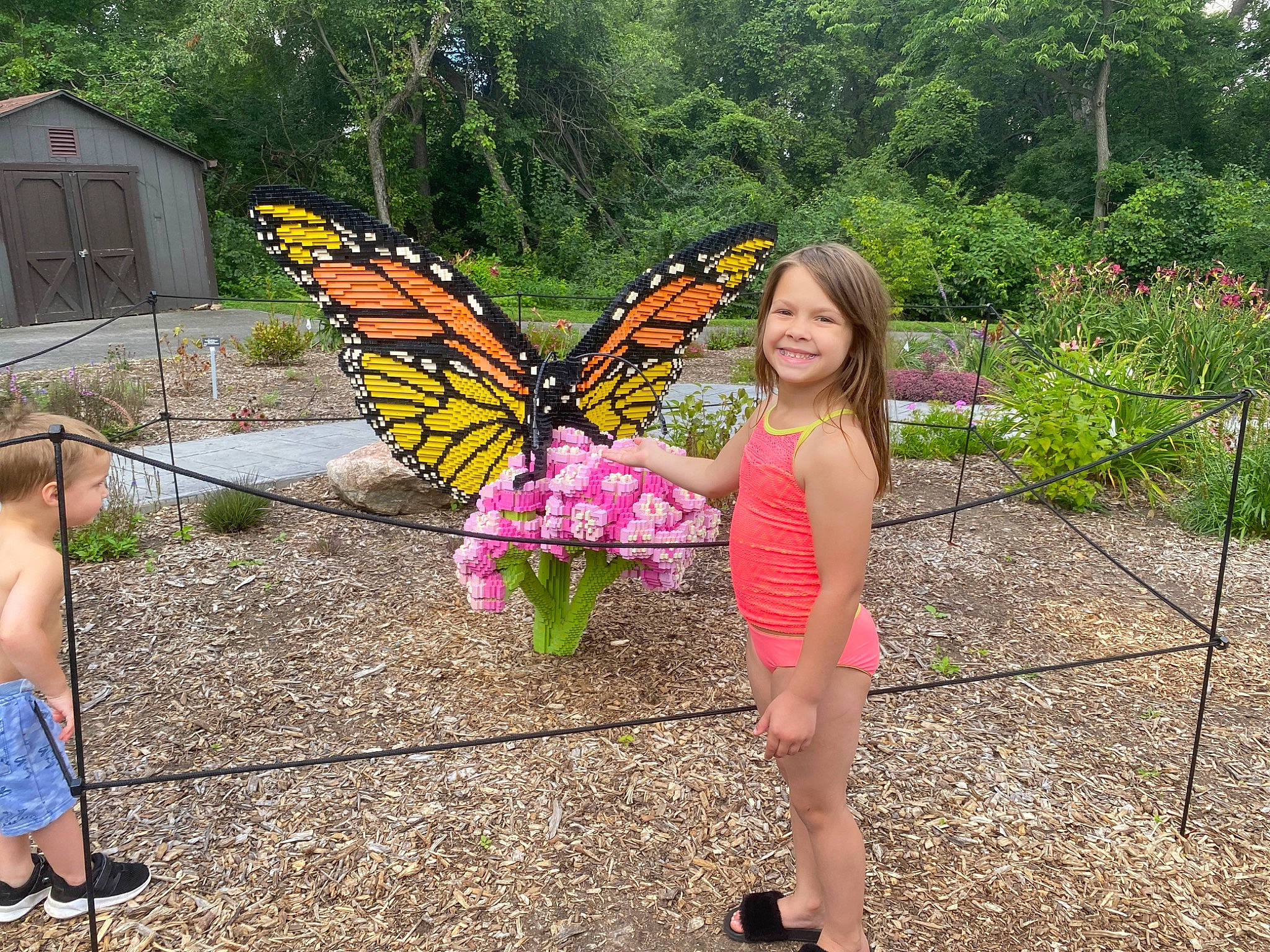 Emma is registered to the contest to win money with this photo: arthropod, botany, butterfly, event, flower, fun, grass, human_leg, insect, joy, leisure, moths_and_butterflies, people_in_nature, person, plant, pollinator, sandal, shrub, smile, summer