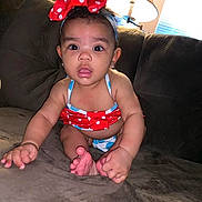 Malani is registered to the contest to win money with this photo: baby, child, polka_dot, bow, swimsuit, couch, indoor, lamp, curtains, wide_eyes, open_mouth, sitting, cute, infant, person, furniture, home, portrait, young_child, expression