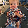 Emmalynn is registered to the contest to win money with this photo: toddler, child, baby, portrait, standing, face, eyes, hair, smiling, curious, party, streamers, confetti, celebration, outdoor, patio, chairs, adult, colorful, photograph