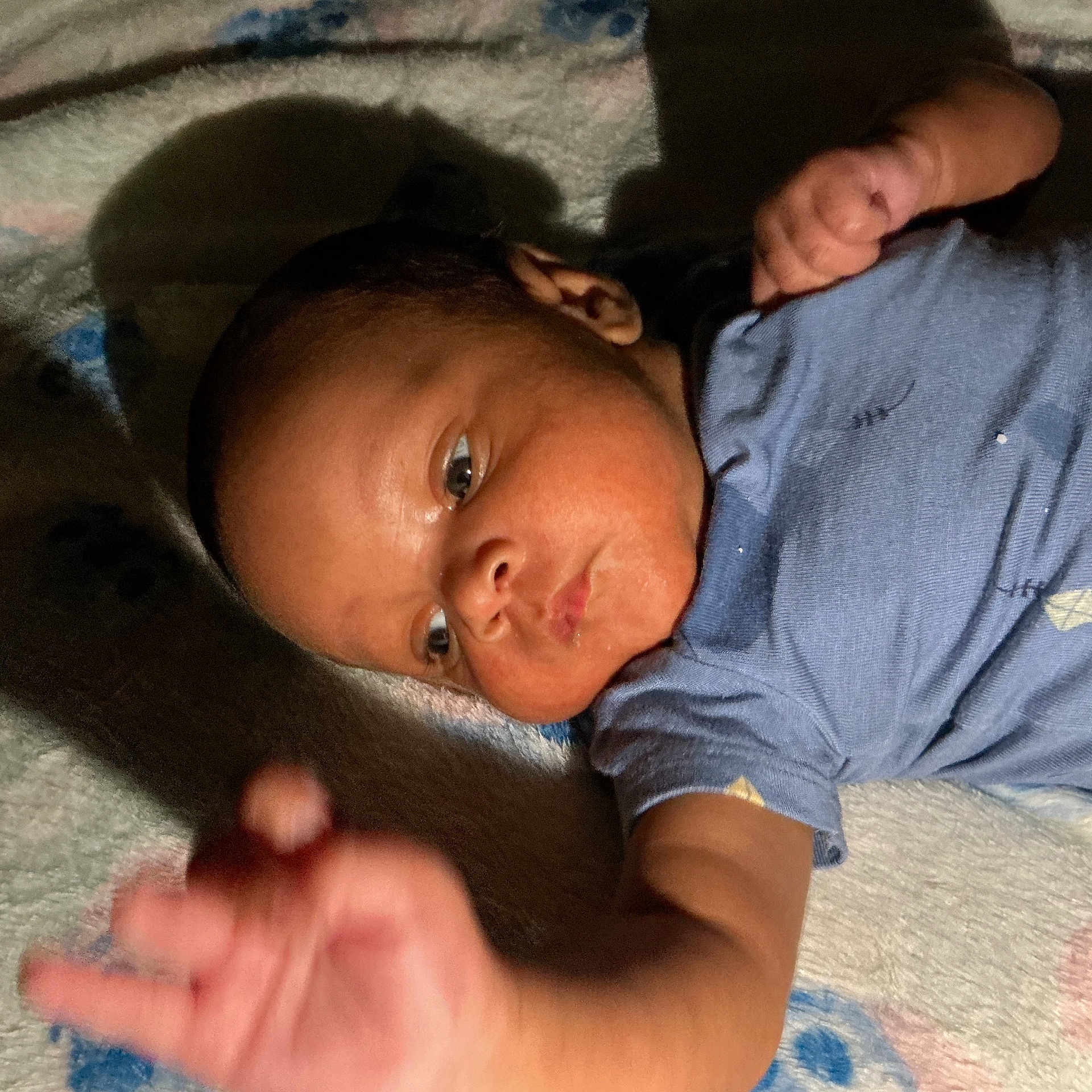 Jakaidens joined the competition — help win amazing prizes! baby, blanket, blue_clothing, candid, child, closeup, curious, expression, face, hand, indoor, infant, lying_down, newborn, person, portrait, shadow, skin, soft_light, young