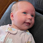 Cordelia is registered to the contest to win money with this photo: baby, infant, smiling, face, blue_eyes, onesie, clothing, soft_fabric, cushion, indoor, portrait, cute, child, newborn, head, skin, happy, closeup, person, baby_girl