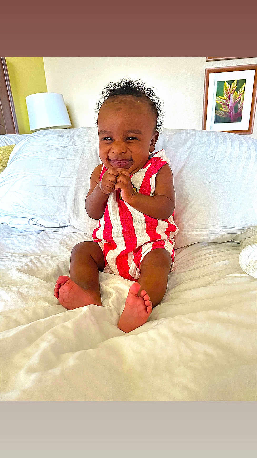 Ropyr joined the competition — help win amazing prizes! baby, child, smiling, bed, white_bedding, red_stripes, romper, indoor, lamp, framed_art, flower_picture, happy, cute, furniture, home, portrait, sitting, skin, foot, infant