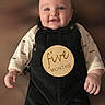 baby, infant, smiling, overalls, black_clothing, sticker, five_months, chubby_cheeks, portrait, cute, child, happy, indoor, soft_background, head, face, person, sleeves, clothing, closeup