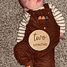 baby, infant, sleepy, brown_overalls, striped_shirt, carpet, socks, plaque, milestone, lying_down, cute, child, indoors, portrait, cozy, two_months, warm_colors, smiling, face, young_child