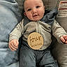 baby, child, infant, smiling, seated, clothing, blue_pillow, cushion, wooden_sign, four_months, face, head, hands, legs, indoor, cozy, comfortable, cute, portrait, person