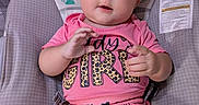 Eleanor is registered to the contest to win money with this photo: baby, child, infant, pink_bow, headband, pink_clothing, baby_seat, blanket, football_pattern, cute, smiling, hands, face, portrait, indoor, toddler, seat, apparel, patterned_clothing, happy