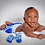 baby, smiling, infant, blue_shorts, boxing_gloves, white_blanket, cute, happy, child, lying_down, portrait, closeup, skin, face, hand, young, playful, accessory, gloves, background