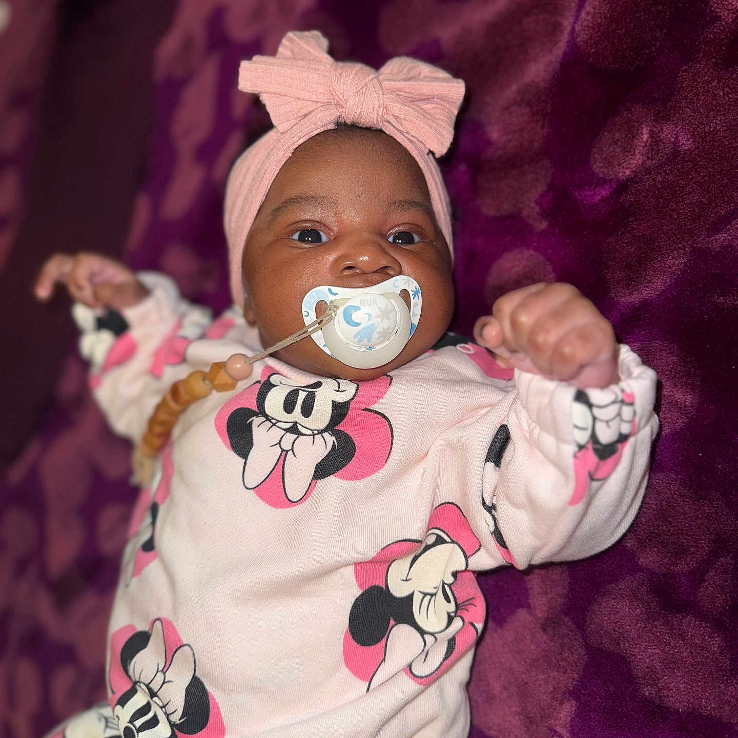 Imany participe au concours pour gagner de l'argent avec cette photo : baby, infant, pacifier, headband, bow, clothing, mickey_mouse, purple_blanket, cute, lying_down, child, portrait, smiling, toddler, indoors, soft_texture, baby_girl, close_up, sleepwear, pink