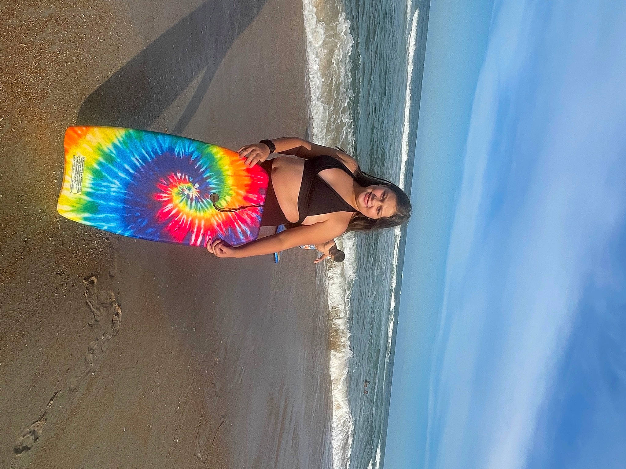 Sophia is registered to the contest to win money with this photo: beach, child, electric_blue, fun, happy, human_leg, joy, leisure, ocean, people_on_beach, person, recreation, sand, sky, smile, surfboard, surfing_equipment, swimwear, thigh, water