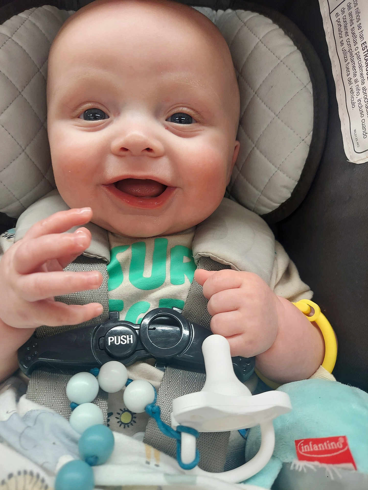 Gunnar is registered to the contest to win money with this photo: baby, smiling, car_seat, pacifier, toy, infant, child, happy, face, hand, close_up, seat_belt, clothing, beads, indoor, cute, skin, head, expression, sitting