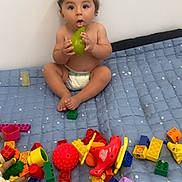 Imran participe au concours pour gagner de l'argent avec cette photo : toddler, child, pear, toy, colorful_toys, quilt, blue_quilt, diaper, indoor, playtime, curious, sitting, bare_chest, soft_lighting, cute, expression, face, hands, feet, playroom