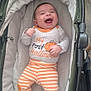 baby, infant, smiling, laughing, stroller, cushion, clothing, pumpkin, halloween, striped_pants, cute, child, indoors, happy, person, orange, white, fabric, celebration, holiday