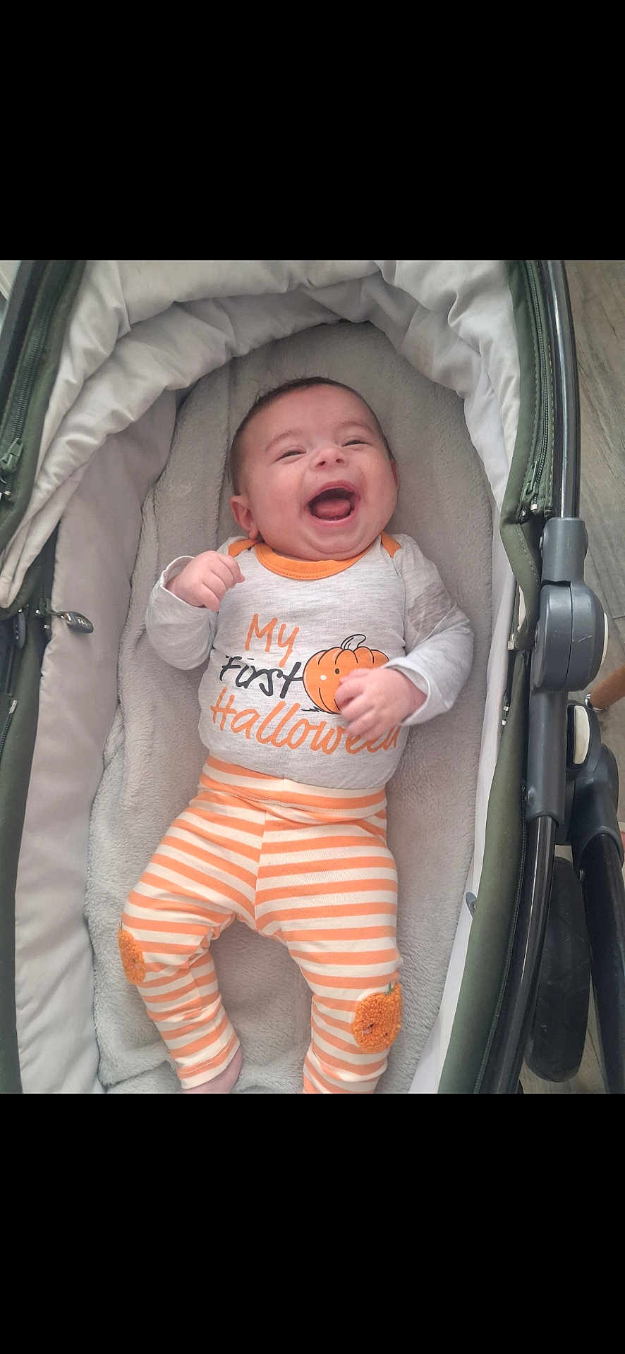 Rio is registered to the contest to win money with this photo: baby, infant, smiling, laughing, stroller, cushion, clothing, pumpkin, halloween, striped_pants, cute, child, indoors, happy, person, orange, white, fabric, celebration, holiday