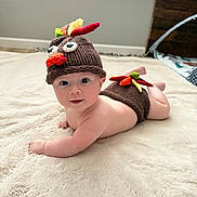 Maddox joined the competition — help win amazing prizes! baby, child, infant, knitted_hat, turkey_hat, diaper_cover, blanket, floor, indoor, cute, soft_texture, window, natural_light, baby_clothing, face, smiling, lying_down, headwear, plush, room