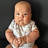 baby, infant, child, portrait, sitting, serious_expression, round_cheeks, face, hands, onesie, elephant_pattern, clothing, chair, indoor, close_up, centered, looking_at_camera, baby_photography, skin, adorable