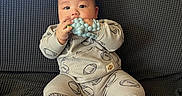 Nixon joined the competition — help win amazing prizes! baby, infant, child, sitting, couch, sofa, teething_toy, toy, smiling, face, portrait, indoors, living_room, clothing, onesie, barefoot, feet, furniture, home, photography