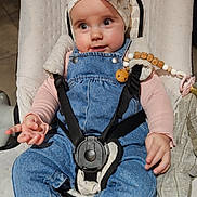 Gulia participe au concours pour gagner de l'argent avec cette photo : baby, infant, bow_headband, denim_overalls, blue_jeans, pink_socks, baby_seat, safety_harness, wooden_beads, pacifier_clip, hands, face, big_eyes, rosy_cheeks, indoor, toy, padded_seat, cute, sitting, looking_up