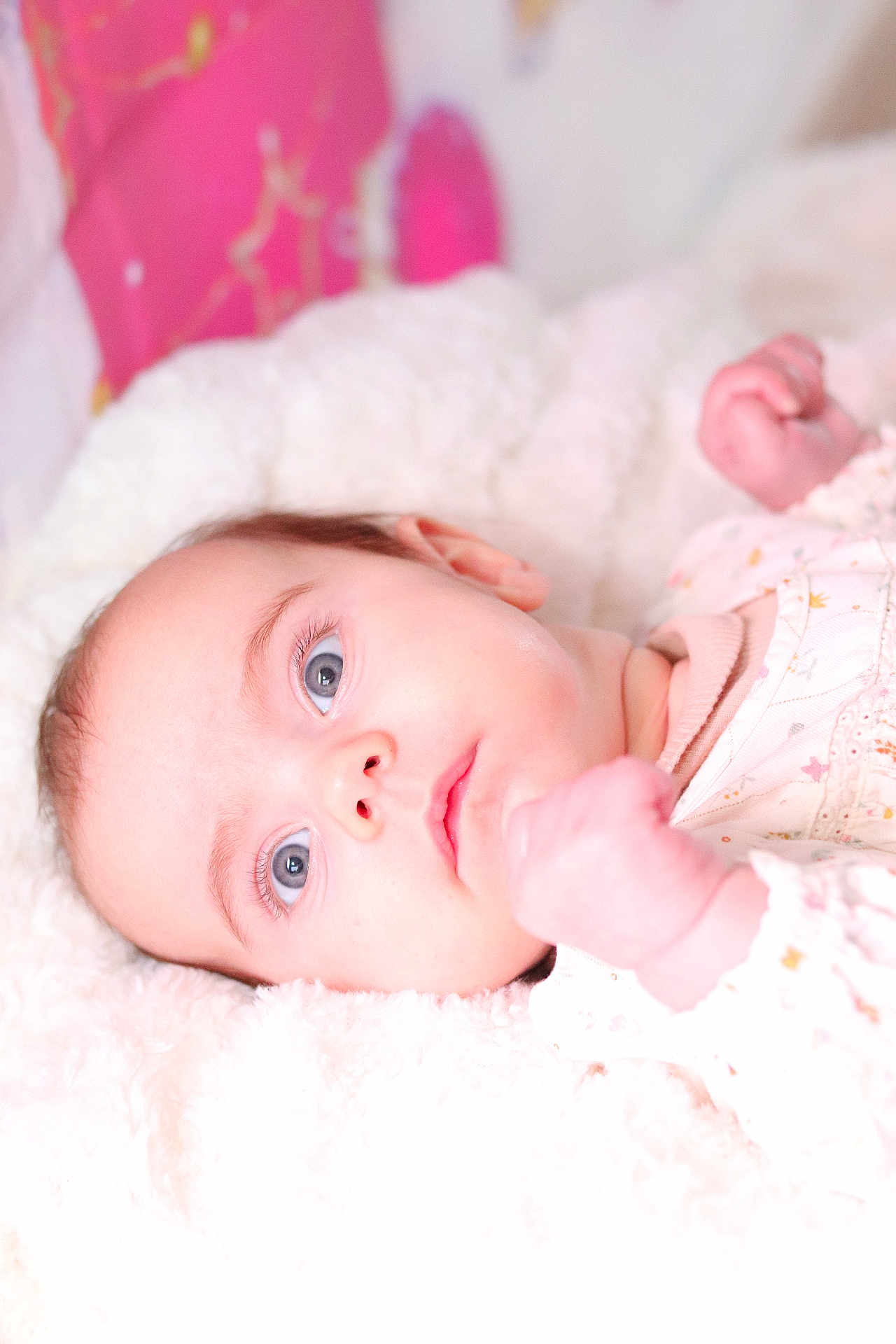 Gulia participe au concours pour gagner de l'argent avec cette photo : baby, infant, blue_eyes, face, close_up, portrait, lying_down, blanket, soft_texture, newborn, onesie, hand, skin, eyelashes, gaze, nursery, pink, plush, bedding, sleepy