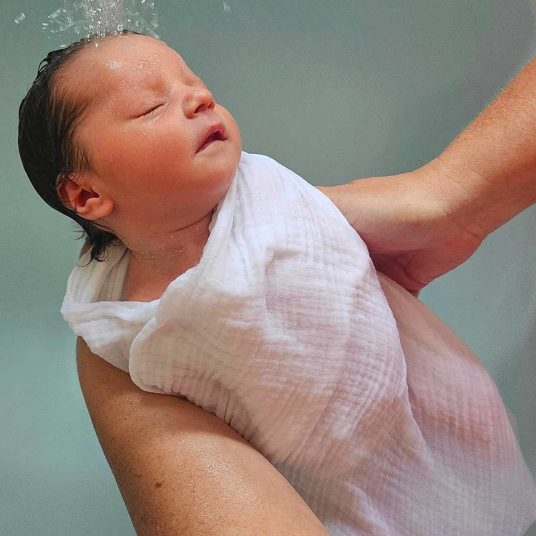Margaux participe au concours pour gagner de l'argent avec cette photo : adult, arm, baby, bath, care, child, closeup, hand, indoor, infant, newborn, peaceful, person, portrait, resting, skin, support, towel, water, wet