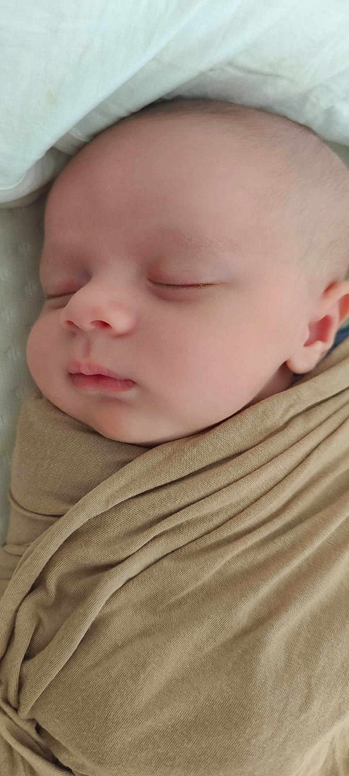 Ziad participe au concours pour gagner de l'argent avec cette photo : baby, sleeping, wrapped, blanket, face, infant, peaceful, soft, serene, closeup, newborn, skin, head, ear, nose, mouth, cheeks, resting, indoors, cozy