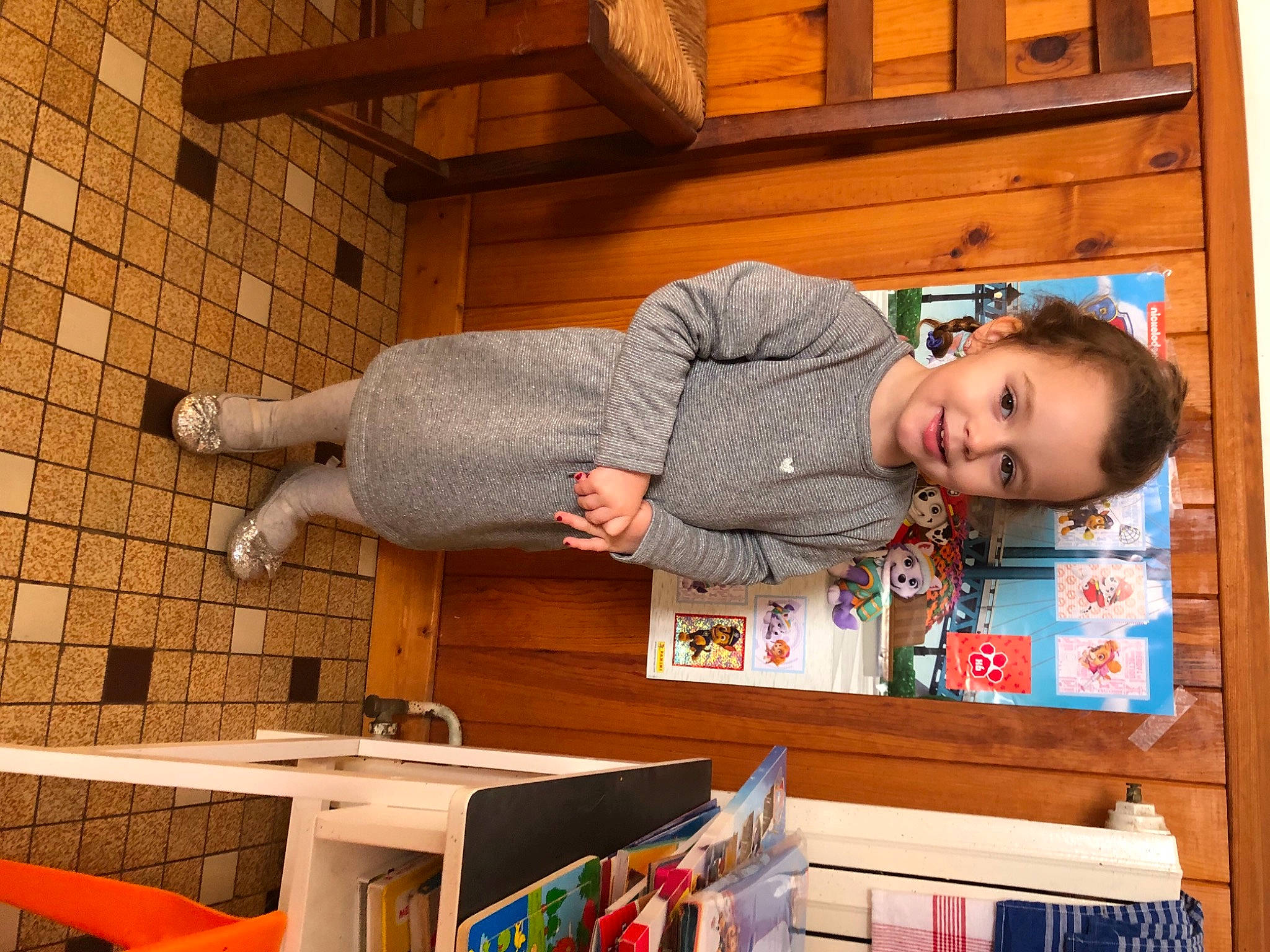 Faustine a rejoint le concours — aidez-le/la à gagner de superbes lots ! baby_toddler_clothing, bookcase, brick, brickwork, building, door, flooring, happy, hardwood, house, joy, person, room, shelf, shelving, sitting, smile, standing, table, toddler