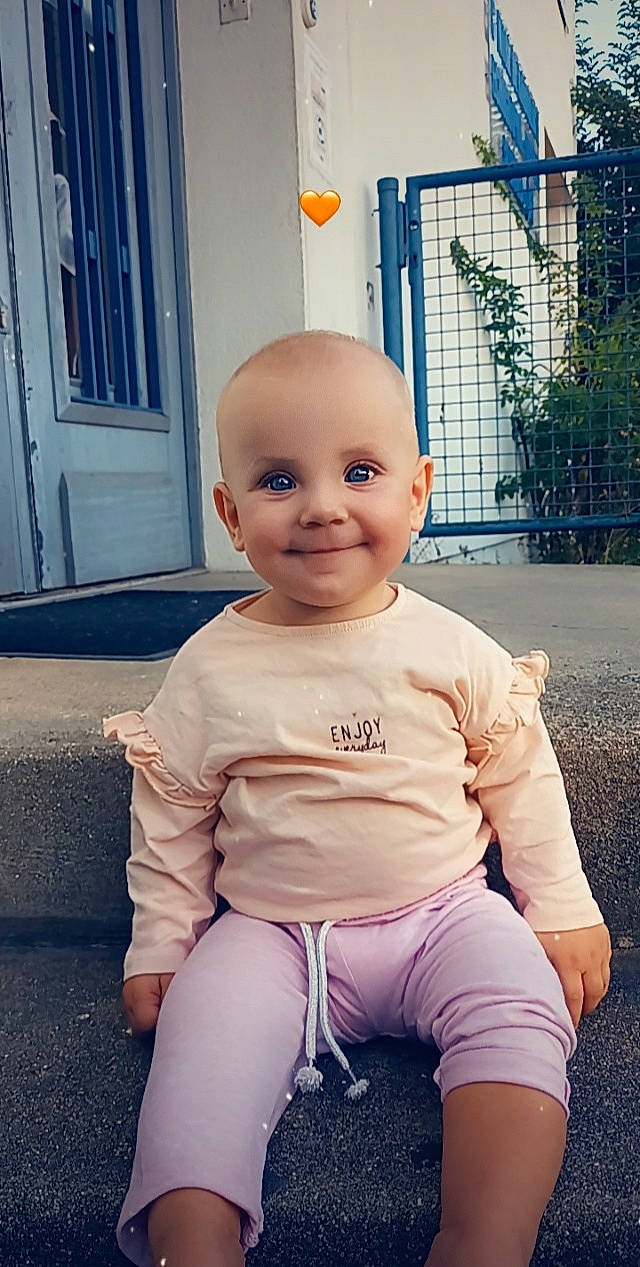 Sofia participe au concours pour gagner de l'argent avec cette photo : baby, baby_toddler_clothing, chin, clothing, door, electric_blue, flooring, happy, head, human_leg, joy, knee, person, pink, sleeve, smile, sportswear, standing, t_shirt, thigh
