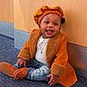 baby, child, smile, orange_coat, beret, jeans, shoes, floor, carpet, wooden_wall, jewelry, happy, sitting, cute, indoor, portrait, person, fashion, accessory, clothing