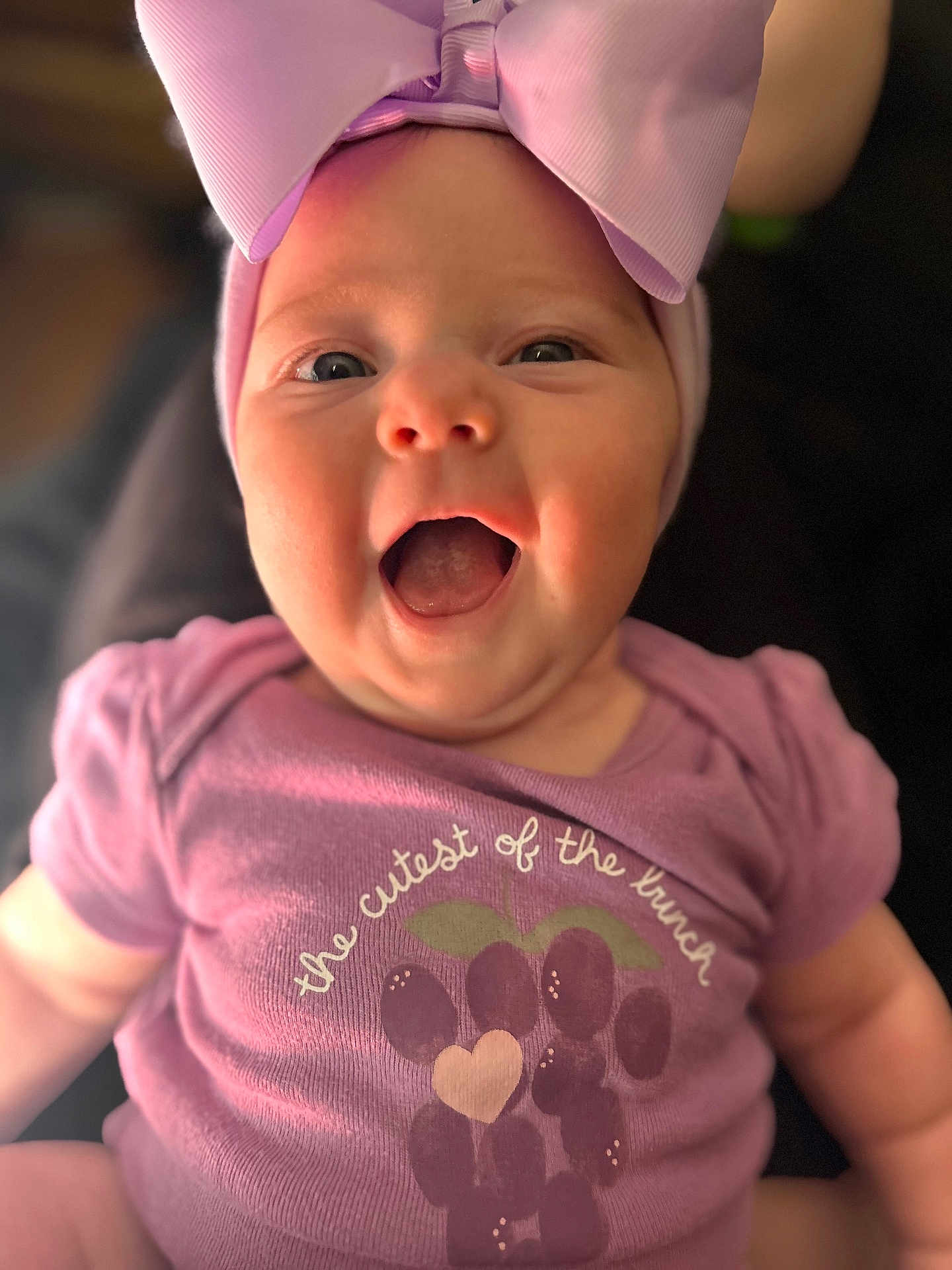 Ember joined the competition — help win amazing prizes! baby, child, infant, smiling, happy, pink_bow, purple_onesie, grape_design, cute, portrait, close_up, face, expression, cheerful, indoors, young_child, apparel, headwear, joyful, person