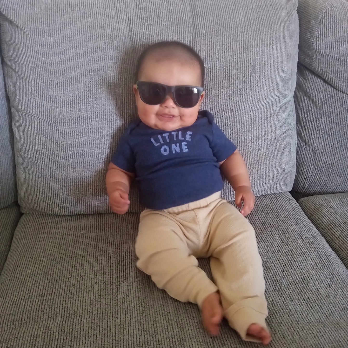 Jesus joined the competition — help win amazing prizes! baby, beige_pants, blue_shirt, casual, child, comfortable, couch, cute, fashion, grey_couch, home, indoor, infant, person, portrait, relaxed, sitting, smile, sunglasses, young_child