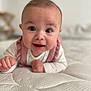 baby, infant, smiling, cute, face, eyes, pink_clothing, white_mattress, texture, lying_down, portrait, child, young, happy, indoors, soft_light, hands, head, ruffles, closeup