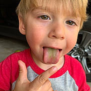 Dominik joined the competition — help win amazing prizes! blonde_hair, boy, car_tire, casual_clothing, child, closeup, expression, face, garage, green_tongue, happy, outdoor, playful, pointing, portrait, red_shirt, skin, smiling, tongue, young