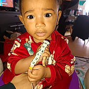 Erwann a rejoint le concours — aidez-le/la à gagner de superbes lots ! toddler, child, baby, indoors, red_clothing, pacifier, hand, toy, expression, face, person, curious, home, furniture, sitting, closeup, person_holding, young_child, cute, portrait