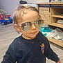 Lowen participe au concours pour gagner de l'argent avec cette photo : toddler, child, indoor, sunglasses, navy_sweatshirt, bear_graphic, toy_car, wooden_floor, cabinet, clothing, reflection, hair, face, person, furniture, shelf, diapers, playroom, casual, cute