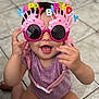 baby, birthday, celebration, child, cupcake, cute, face, floor, fun, glasses, happy, indoors, party_accessory, person, pink, playful, purple_clothing, smile, sunglasses, toddler