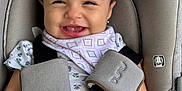 Camila is registered to the contest to win money with this photo: baby, child, car_seat, smiling, bow, face, happiness, infant, clothing, safety_harness, cute, portrait, indoors, seatbelt, happy, person, closeup, head, baby_girl, comfort