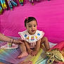 Camila is registered to the contest to win money with this photo: baby, child, pink_bow, birthday, balloons, metallic_balloons, tablecloth, rainbow_colors, hands, celebration, party, smiling, cute, infant, pink_background, decorations, sitting, cute_outfit, festive, portrait
