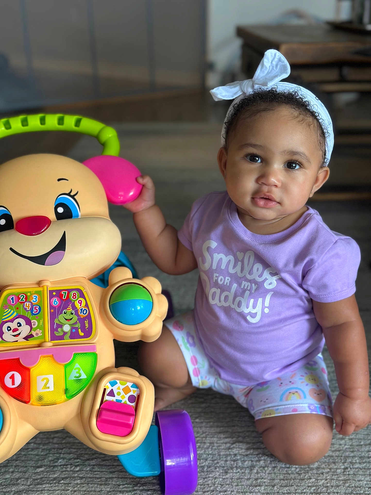Raya joined the competition — help win amazing prizes! toddler, child, baby, headband, purple_shirt, toy_walker, colorful_toy, smiling_toy, indoor, carpet, playtime, cute, sitting, expression, bright_colors, person, portrait, happy, childhood, floor