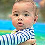baby, infant, child, swimming_pool, water, striped_shirt, rashguard, wet_hair, big_eyes, rosy_cheeks, closeup, portrait, holding, adult_hand, arm, cute, skin, face, parental_care, blue
