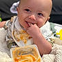 Dean joined the competition — help win amazing prizes! baby, infant, messy, bib, food, container, orange_food, blanket, smiling, chewing, finger_in_mouth, closeup, cute, indoor, person, head, face, eyes, skin, clothing