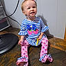 toddler, child, smiling, sitting, striped_clothing, bow, pink, blue, long_sleeves, pants, patterned_pants, floor, wooden_floor, indoor, hair_bow, happy, cute, person, baby, playful