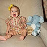 baby, infant, child, sitting, smiling, laughing, portrait, indoor, couch, cushion, stuffed_animal, elephant_toy, floral_outfit, yellow_bow, baby_girl, six_months, milestone, wallpaper, home, cozy