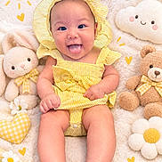 Karina is registered to the contest to win money with this photo: baby, infant, child, smiling, happy, portrait, yellow_outfit, gingham, bonnet, tongue_out, lying_down, teddy_bear, stuffed_animal, flowers, daisies, cloud_pillow, hearts, blanket, indoor, colorful