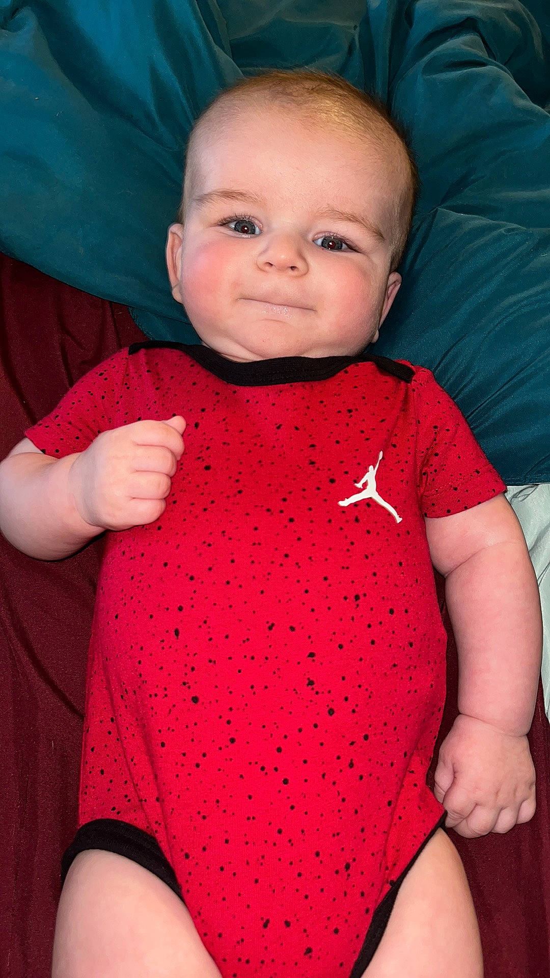 Deegan is registered to the contest to win money with this photo: arm, baby, baby_toddler_clothing, cheek, chin, collar, finger, head, human_body, joint, lip, neck, one_piece_garment, organ, person, pink, skin, sleeve, smile, textile